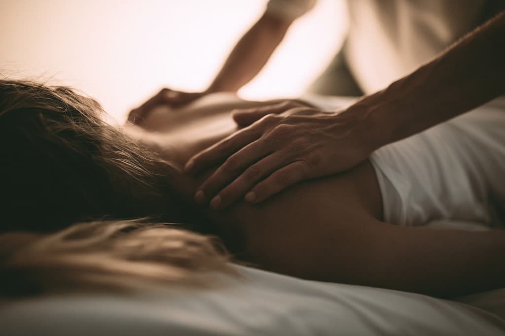 Nahaufnahme einer osteopathischen Behandlung: Hände eines Therapeuten auf dem Rücken eines Patienten